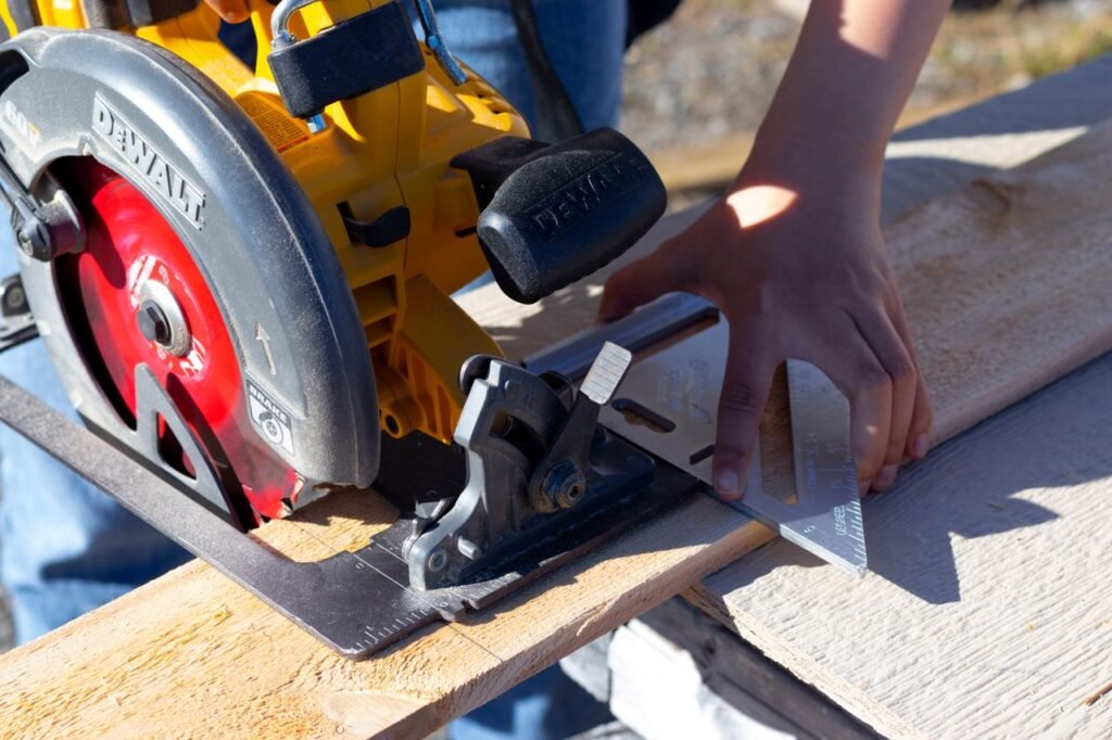 Close-up of a woman using a circular saw and speed square for woodworking outdoors.