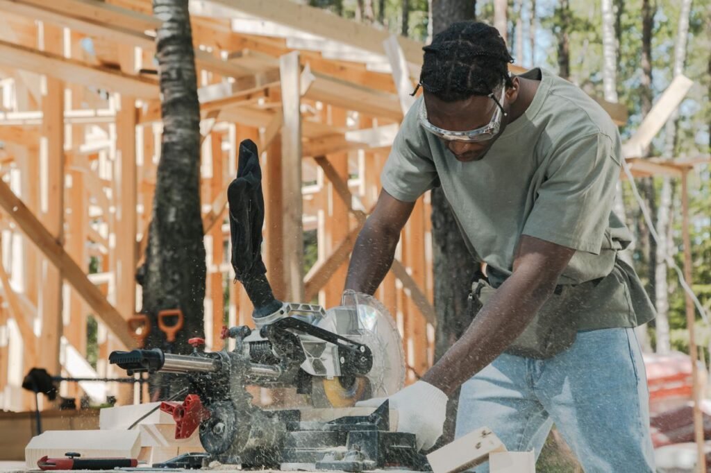 A carpenter using a miter saw at an outdoor construction site.