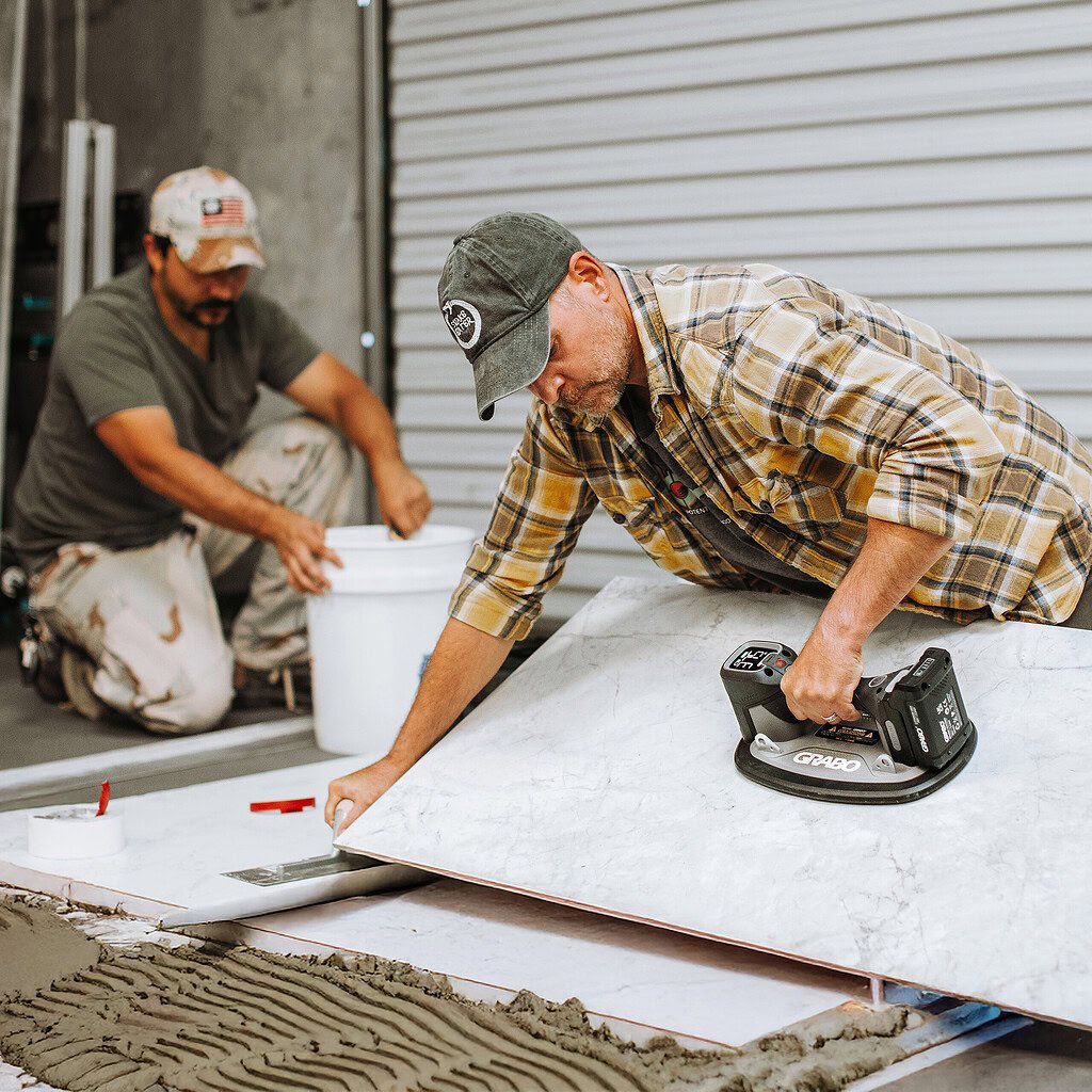 Installer using a GRABO Pro Brushless vacuum lifter to position a large tile